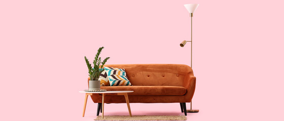 Cozy brown sofa with cushions on pink background