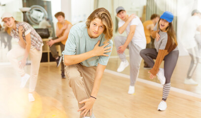 Fototapeta na wymiar Group of positive teenagers dancing modern dance in ballroom.