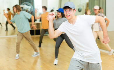 Fototapeta na wymiar Group of active teens rehearsing modern dance in studio.