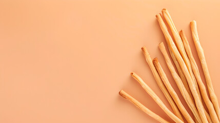 thin long grissini bread sticks on side of pastel colored cream orange background with place for text - obrazy, fototapety, plakaty