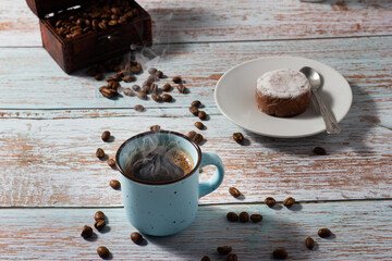 Cup of steaming coffee, homemade cookie and coffebeans on wooden background.