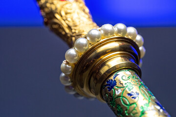 Detail of a golden scepter with white pearls.