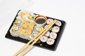 Sushi to go in a black takeaway box with wooden chopsticks on white background 