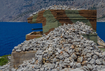 The barrel of the gun in a concrete bunker painted in camouflage