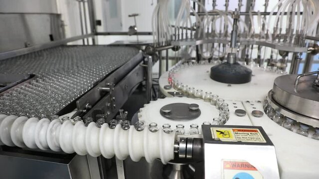 vaccine making machine. Injections in row of empty glass vials moving filing process with liquid medicine production in a pharmaceutical manufacturing company. factory making medicine drugs.