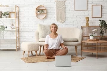 Fotobehang Mature woman with laptop meditating at home. Online yoga classes © Pixel-Shot