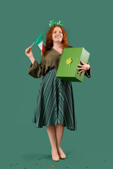 Young redhead woman with gift box and Irish flag on green background. St. Patrick's Day celebration