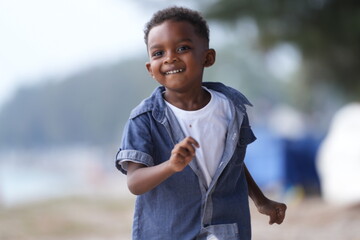 Mixed race African and Asian boy is playing at the outdoor area. smiling happy boy has fun running...