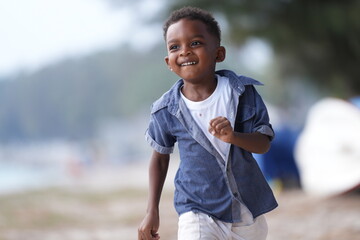 Mixed race African and Asian boy is playing at the outdoor area. smiling happy boy has fun running...