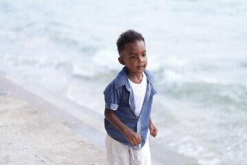 Mixed race African and Asian boy is playing at the outdoor area. smiling happy boy has fun running on the beach. portrait of boy lifestyle with a unique hairstyle.