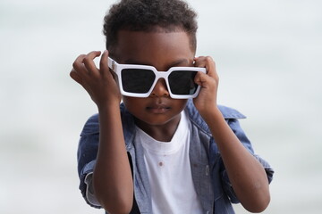 Mixed race African and Asian boy is playing at the outdoor area. smiling happy boy has fun running on the beach. portrait of boy lifestyle with a unique hairstyle.