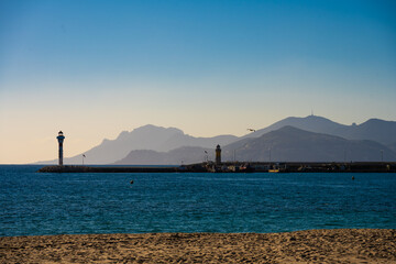 Serene Evening at Cannes Beach with Lighthouse and Mountain Silhouette, France