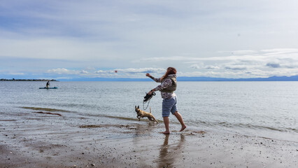 Girl playing with dog on the beach