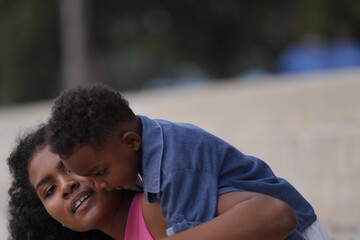 Mixed race African and Asian mother and boy is playing at the outdoor area. smiling happy family have fun running on the beach. portrait of mom and kid lifestyle with a unique hairstyle.