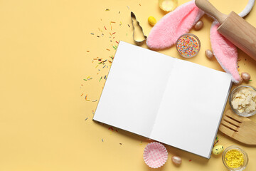 Blank notepad for recipes with Easter decor, colorful sprinkles and baking tools on yellow background