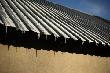 Steel roof slope. Icicles on the roof. Garage roof
