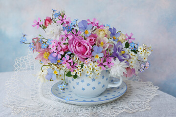 Bouquet of spring and summer flowers in a cup on the table, roses, aquilegia, spirea, forget me not flowers, pansies, violet, beautiful postcard, still life, blur. - 756066751