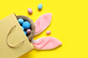 Shopping bag with fluffy bunny ears with nest and Easter eggs on yellow background