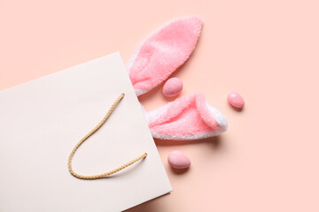 Shopping bag with fluffy bunny ears and Easter eggs on beige background