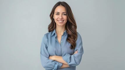 Happy young smiling confident professional business woman wearing blue shirt, pretty stylish female executive looking at camera, standing arms crossed isolated at gray background
