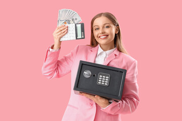 Beautiful young happy woman with safe box, money and calculator on pink background