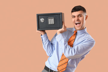 Happy young man with safe box on brown background