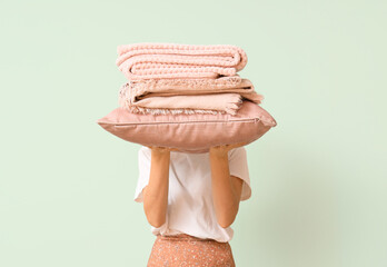 Woman with pillow and folded warm plaids on light background