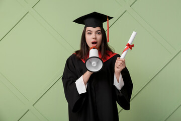 Female graduating student with diploma and megaphone on green wooden background