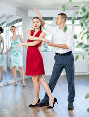 Man and girl take dance lessons from experienced teacher. Couple in stage costumes practices waltz...