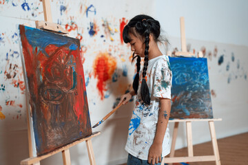 Schoolgirl paint on canvas show creative idea in drawing class. Kid paint canvas all around use...