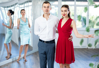 Couple learns dancing during individual lesson in classical and modern dance studio. Young girl with partner wearied in stage costumes trains performance of slow waltz dance.