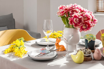 Festive Easter table setting with vase of flowers and painted eggs