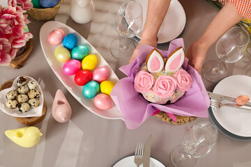 Female hands decorating festive table with Easter cake
