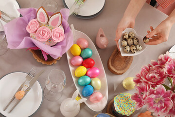 Female hands decorating festive Easter table with bowl of eggs