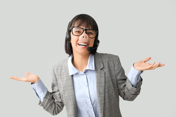 Funny young female technical support worker with headset and pig nose on grey background. Fool's day