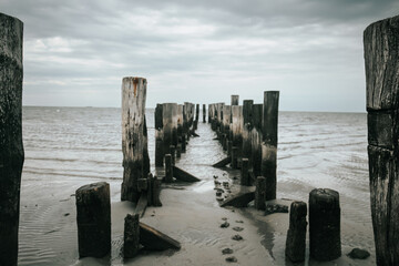  wooden pillars in the sea. Old wooden pier on a cloudy day.sea photo wallpaper. Low tide...