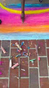 Child draws with chalk on sidewalk in local arts festival