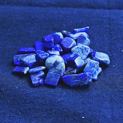 Several lapis lazuli gem stones or healing crystals laying on cotton fabric. 