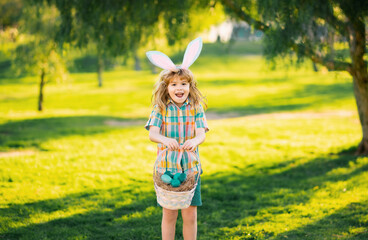 Bunny boy. Kids in bunny ears on Easter egg hunt in garden. Children with colorful eggs in grass....