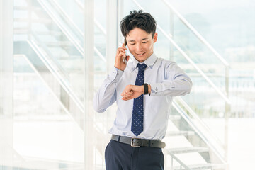 オフィスビルでスマホで電話する若いアジア人ビジネスマン
