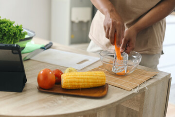 Hand grating fresh ripe carrot at kitchen table. Healthy food concept