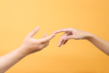 Man and woman touching tip fingers each other over yellow background. Love, connect, help concepts.