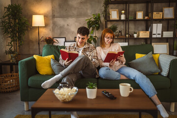 Obraz premium man and woman caucasian adult couple read books at home on sofa bed