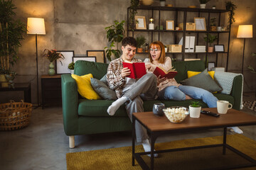 Obraz premium man and woman caucasian adult couple read books at home on sofa bed