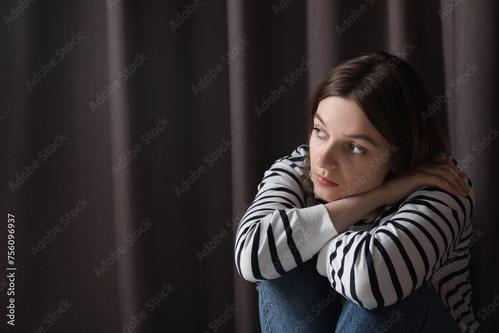 Canvas Prints Sad young woman near curtains indoors, space for text