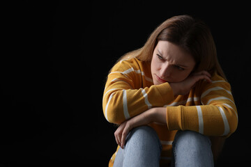 Portrait of sad woman on black background, space for text