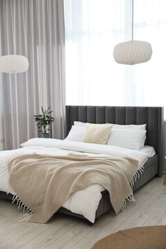 Soft beige plaid on bed in stylish bedroom. Interior design