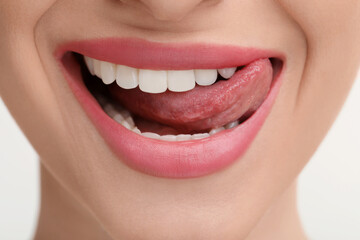 Young woman licking her teeth on white background, closeup