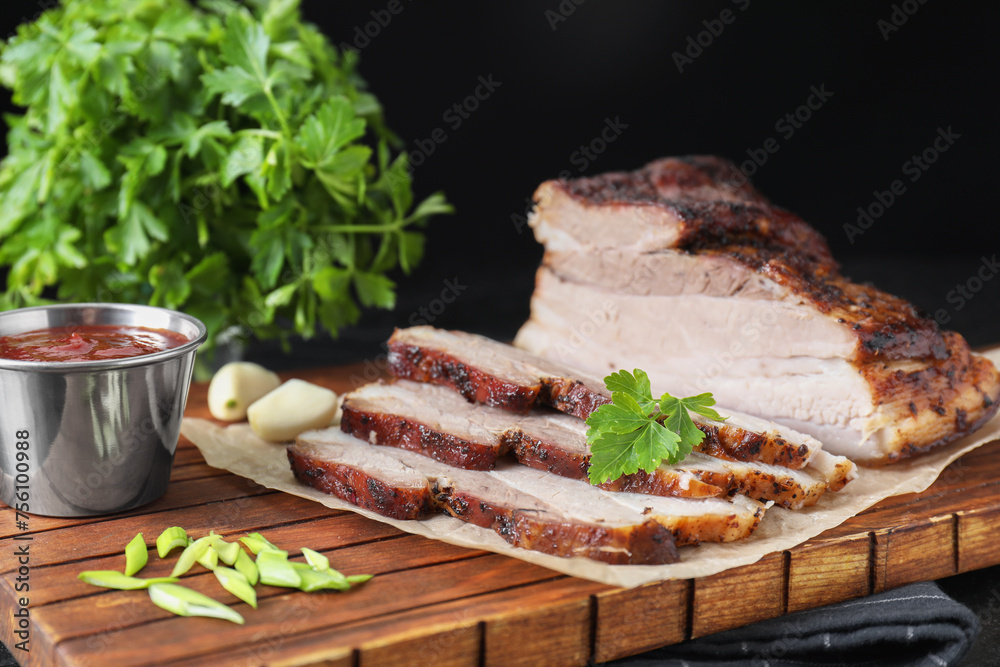 Wall mural pieces of baked pork belly served with sauce and parsley on table, closeup