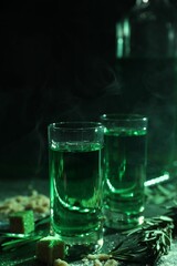 Absinthe in shot glasses, rosemary and brown sugar on table, closeup. Alcoholic drink